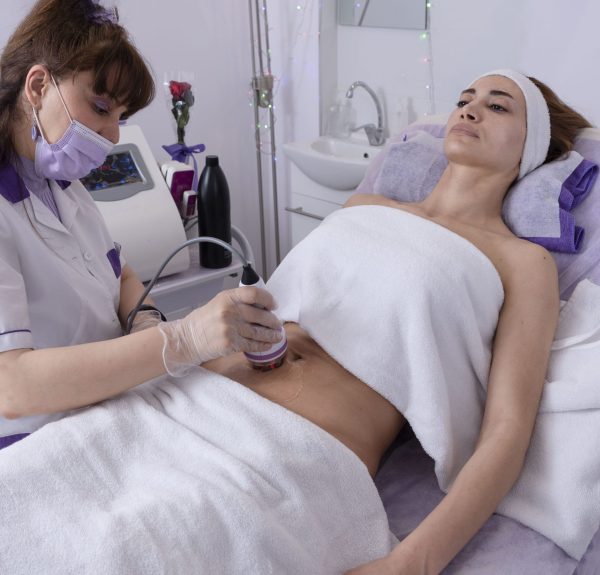 cosmetologist does radiofrequency body treatment of abdomen ,Body sculpting non-surgical. anti-cellulite and anti-fat therapy in beauty salon.